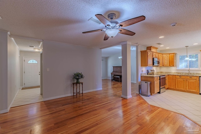 4679 E Spencer Field Rd, Pace, FL 32571 - kitchen with hanging light fixtures, light wood-style floors, appliances with stainless steel finishes, ceiling fan, and a textured ceiling