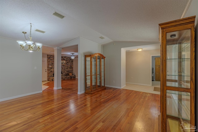 empty room featuring a fireplace, light wood-type flooring, lofted ceiling, and a textured ceiling