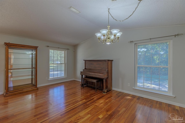 interior space with hardwood / wood-style floors, a healthy amount of sunlight, vaulted ceiling, and a chandelier