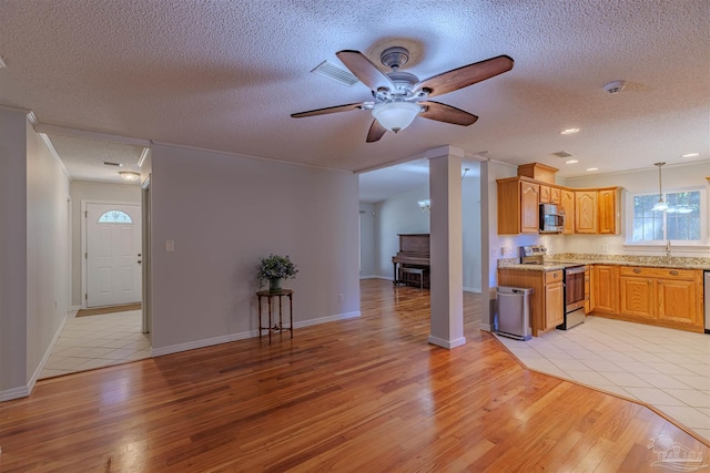 kitchen with ceiling fan, light hardwood / wood-style flooring, decorative light fixtures, a textured ceiling, and appliances with stainless steel finishes