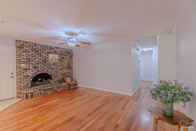 4679 E Spencer Field Rd, Pace, FL 32571 - unfurnished living room featuring wood finished floors, ceiling fan, a brick fireplace, visible vents, and a textured ceiling