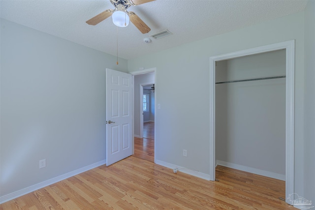 unfurnished bedroom with a closet, a textured ceiling, light hardwood / wood-style floors, and ceiling fan