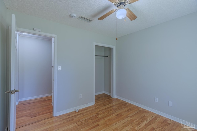 unfurnished bedroom featuring ceiling fan, light hardwood / wood-style floors, and a textured ceiling