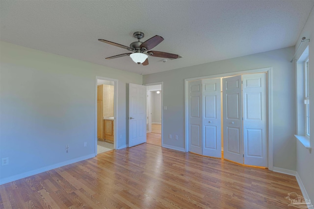 unfurnished bedroom featuring ceiling fan, ensuite bathroom, a textured ceiling, a closet, and light wood-type flooring