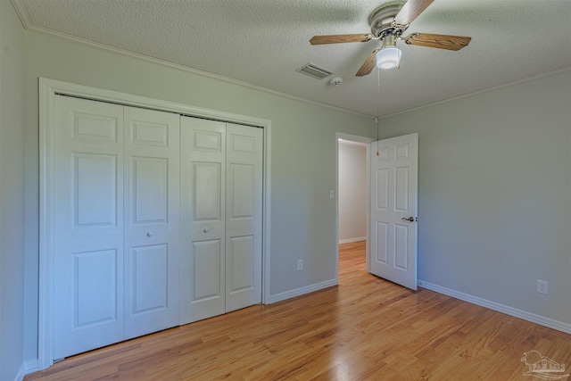 unfurnished bedroom featuring a textured ceiling, ceiling fan, crown molding, light hardwood / wood-style floors, and a closet