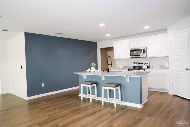 kitchen featuring sink, white cabinetry, dark hardwood / wood-style flooring, an island with sink, and stainless steel appliances