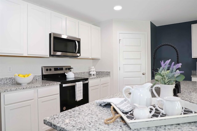 kitchen with white cabinetry, stainless steel appliances, and light stone counters