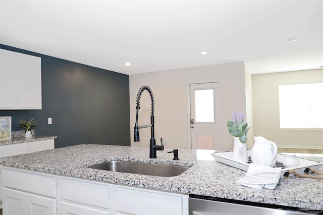 kitchen with white cabinetry, sink, and light stone counters