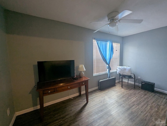 living area featuring baseboards, a ceiling fan, and wood finished floors