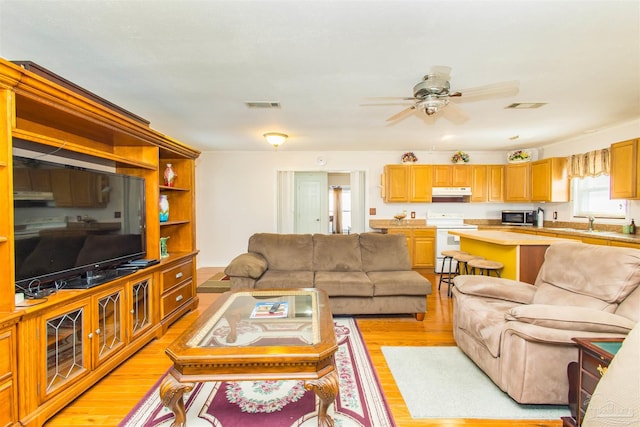 living room featuring sink, ceiling fan, and light hardwood / wood-style flooring