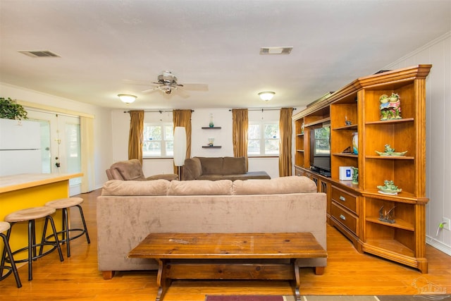 living room featuring ornamental molding, ceiling fan, and light hardwood / wood-style flooring