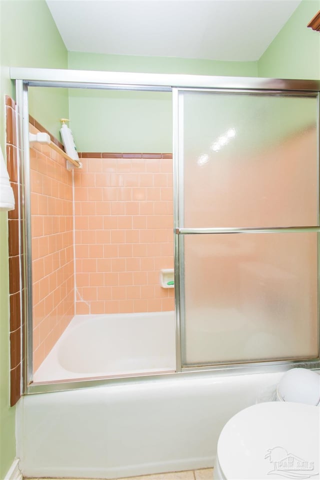 bathroom with combined bath / shower with glass door and toilet