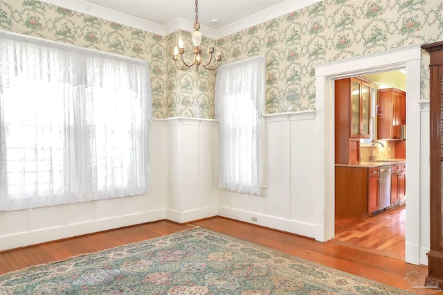 spare room featuring a sink, wallpapered walls, a wainscoted wall, and wood finished floors