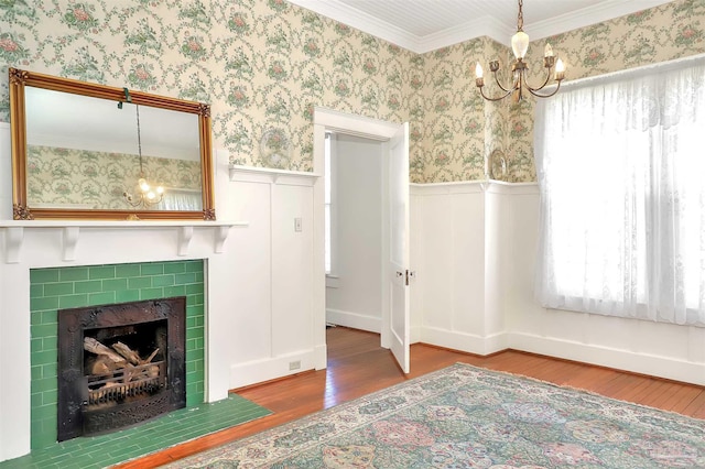 unfurnished living room with wallpapered walls, wood finished floors, a wainscoted wall, and an inviting chandelier