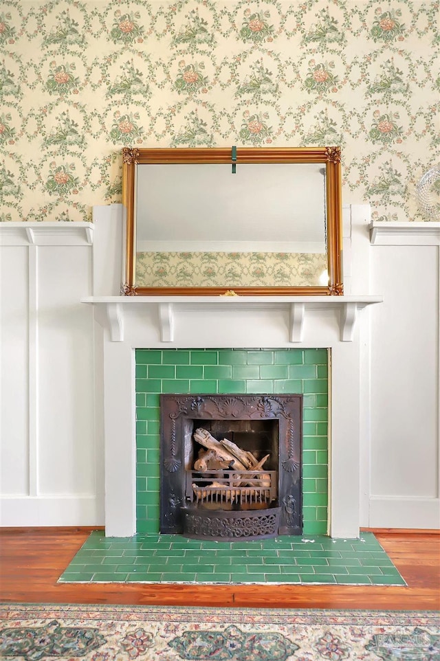 interior details with wallpapered walls, wainscoting, wood finished floors, and a tile fireplace