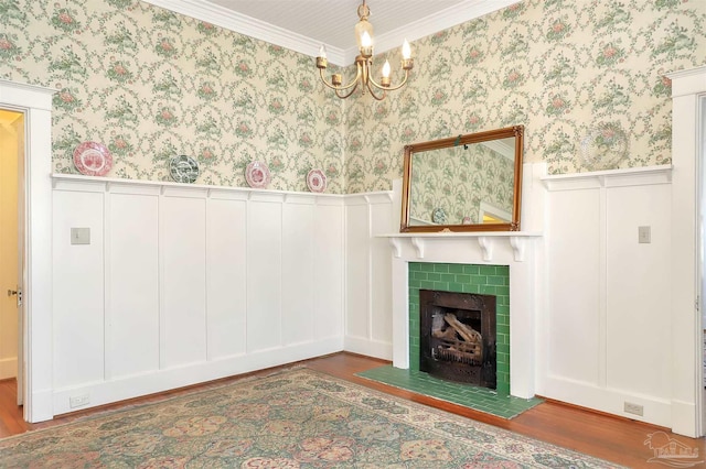 unfurnished living room featuring an inviting chandelier, wainscoting, wood finished floors, a tile fireplace, and wallpapered walls