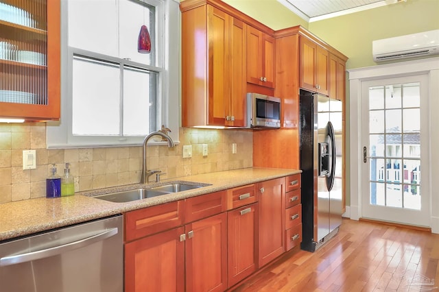 kitchen featuring a sink, light countertops, stainless steel appliances, an AC wall unit, and backsplash