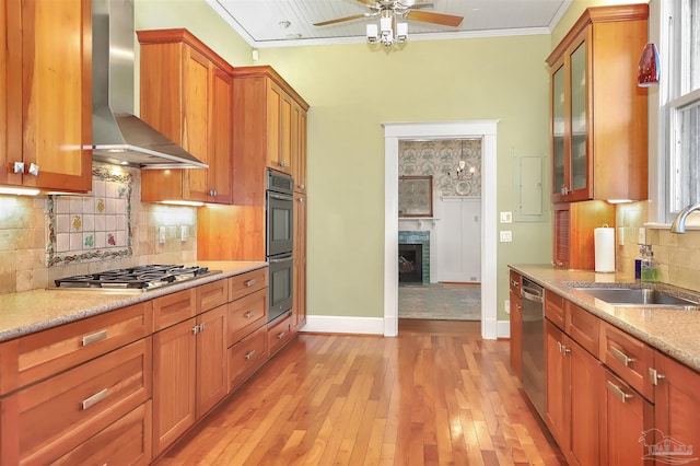 kitchen featuring a sink, wall chimney range hood, appliances with stainless steel finishes, brown cabinets, and crown molding