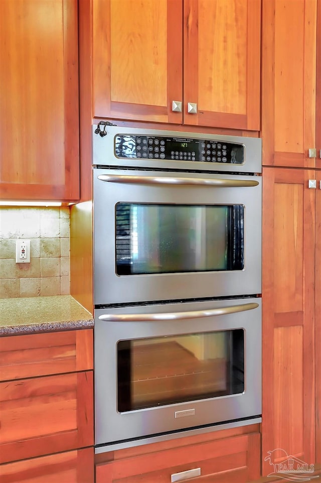 kitchen featuring light stone countertops, double oven, and decorative backsplash