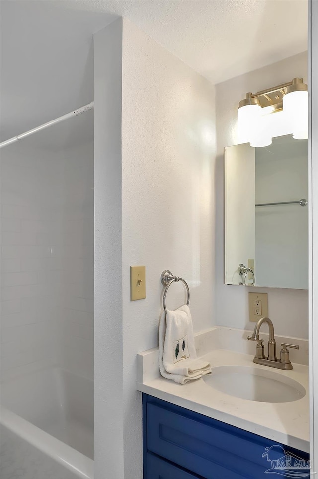 bathroom featuring a textured ceiling, a textured wall, a shower, and vanity