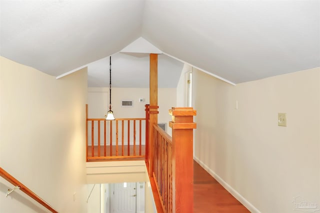 interior space featuring baseboards, visible vents, wood finished floors, vaulted ceiling, and an upstairs landing