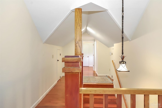 hallway featuring lofted ceiling, wood finished floors, and baseboards