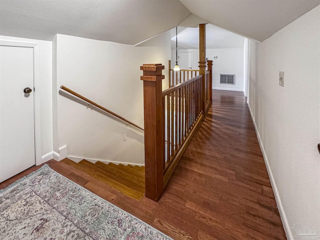 stairway with visible vents, vaulted ceiling, baseboards, and wood finished floors