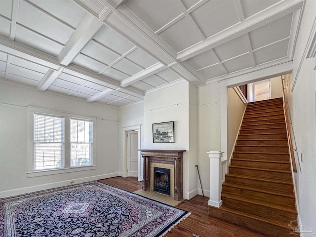 living area with coffered ceiling, a fireplace with flush hearth, wood finished floors, baseboards, and stairway