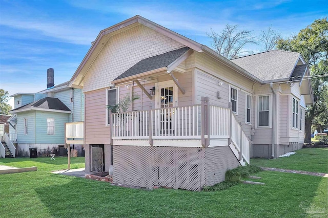 rear view of property with a lawn and roof with shingles