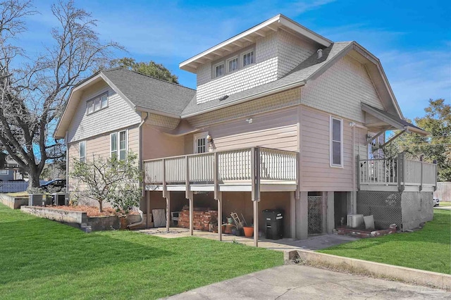 back of property with a yard, a shingled roof, a patio area, and a wooden deck