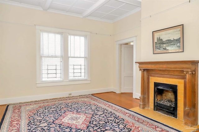 living area featuring a fireplace with flush hearth, crown molding, baseboards, and wood finished floors