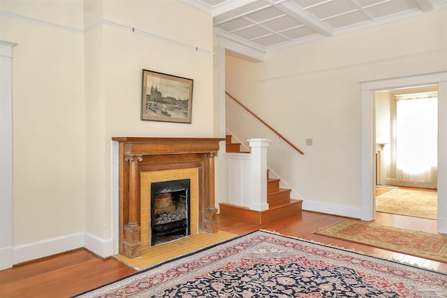 unfurnished living room with coffered ceiling, baseboards, and wood finished floors