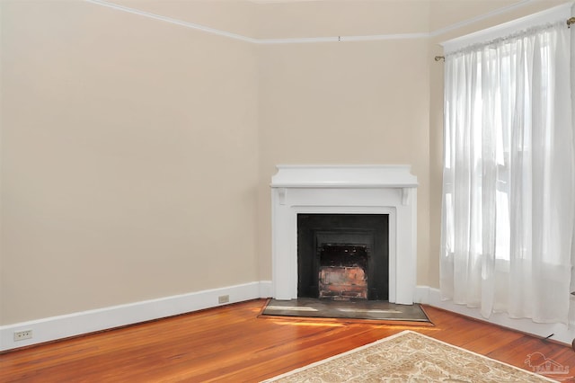 unfurnished living room featuring a fireplace with flush hearth, baseboards, and wood finished floors