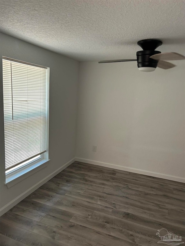 unfurnished room featuring a textured ceiling, ceiling fan, dark wood-type flooring, and a wealth of natural light