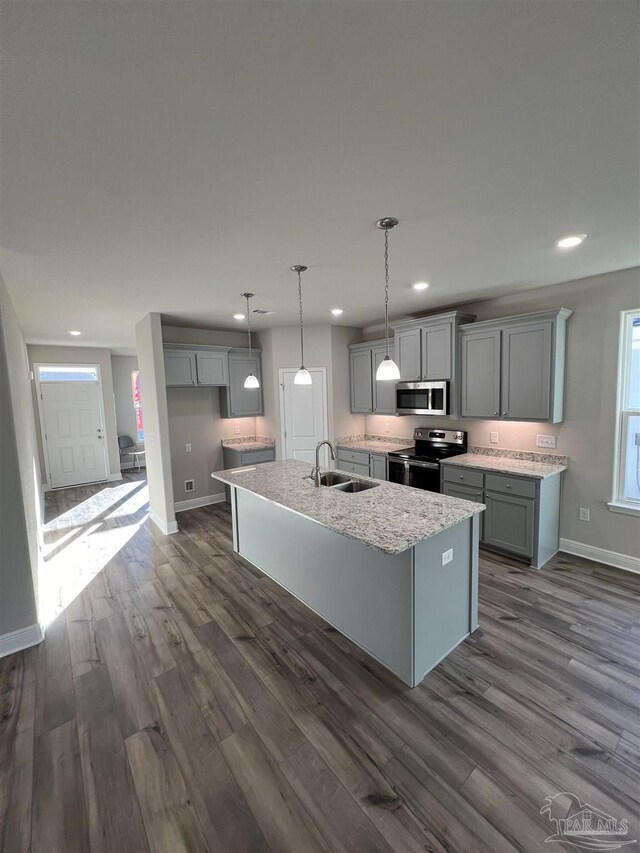 kitchen with sink, appliances with stainless steel finishes, dark hardwood / wood-style flooring, and an island with sink