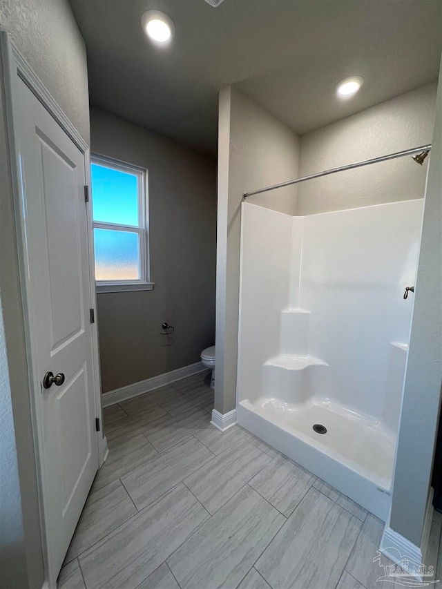 bathroom with toilet, tile patterned floors, and walk in shower