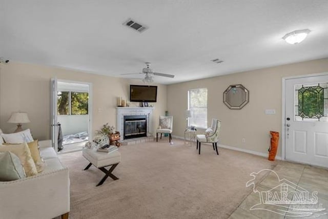 living room with a wealth of natural light, ceiling fan, and light carpet