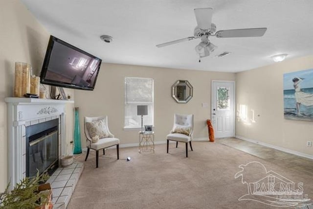 living area featuring a fireplace, light carpet, and ceiling fan