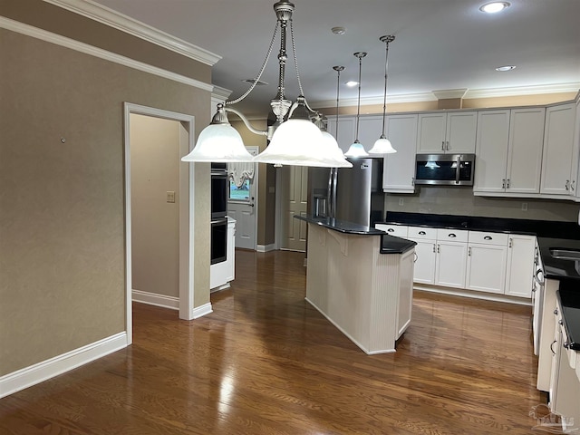 kitchen featuring a kitchen island, dark countertops, dark wood finished floors, stainless steel appliances, and crown molding