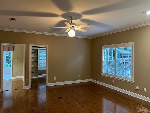 empty room with wood finished floors, visible vents, and ornamental molding