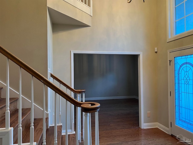 foyer featuring stairway, wood finished floors, baseboards, and a towering ceiling