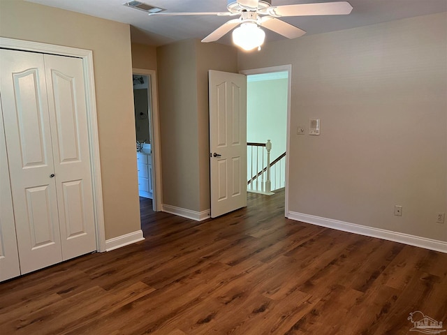 unfurnished bedroom featuring a closet, baseboards, dark wood-type flooring, and ceiling fan