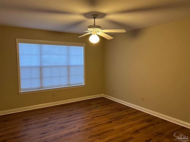 empty room with baseboards, a ceiling fan, and dark wood-style flooring