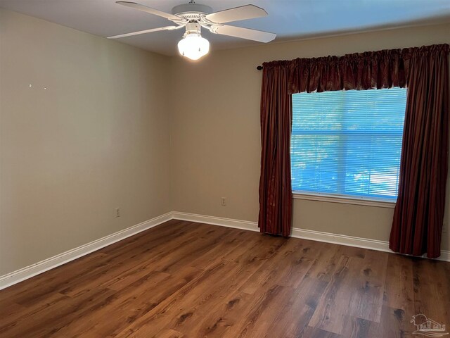 empty room with baseboards, a ceiling fan, and dark wood-style flooring