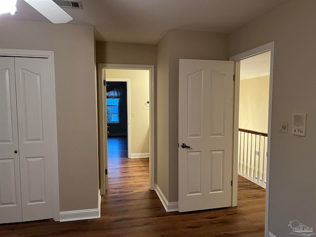 corridor featuring baseboards and dark wood-style flooring