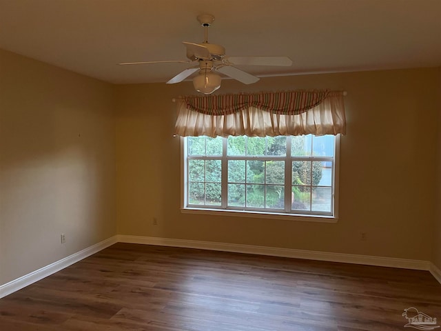 spare room with dark wood finished floors, baseboards, and ceiling fan