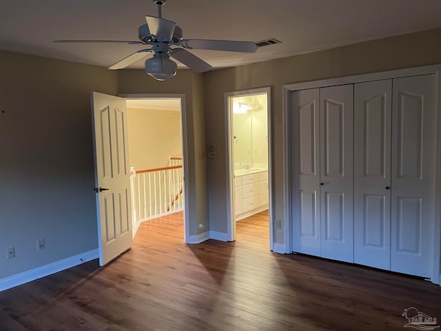 unfurnished bedroom featuring dark wood-style floors, visible vents, baseboards, ceiling fan, and a closet