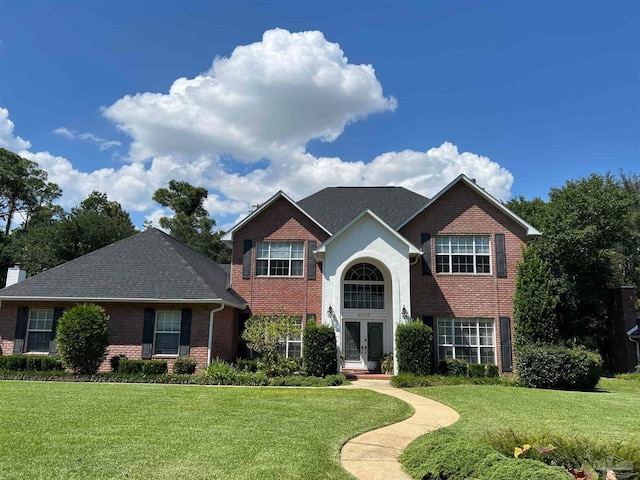 traditional-style home with brick siding, french doors, a chimney, and a front lawn