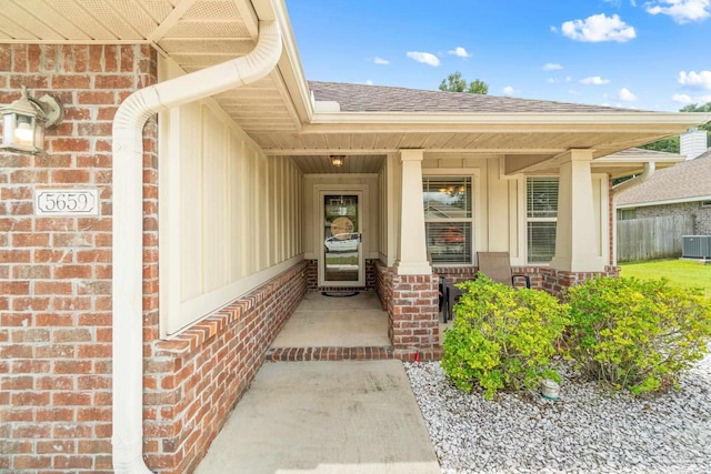 view of exterior entry with covered porch and central AC unit