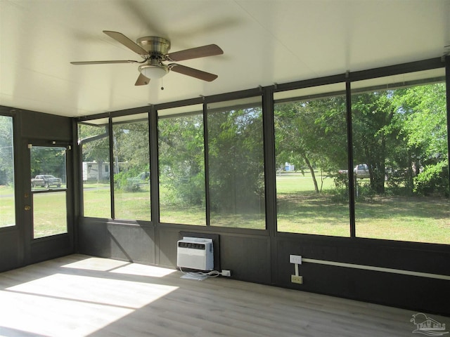 unfurnished sunroom with a wall unit AC and ceiling fan